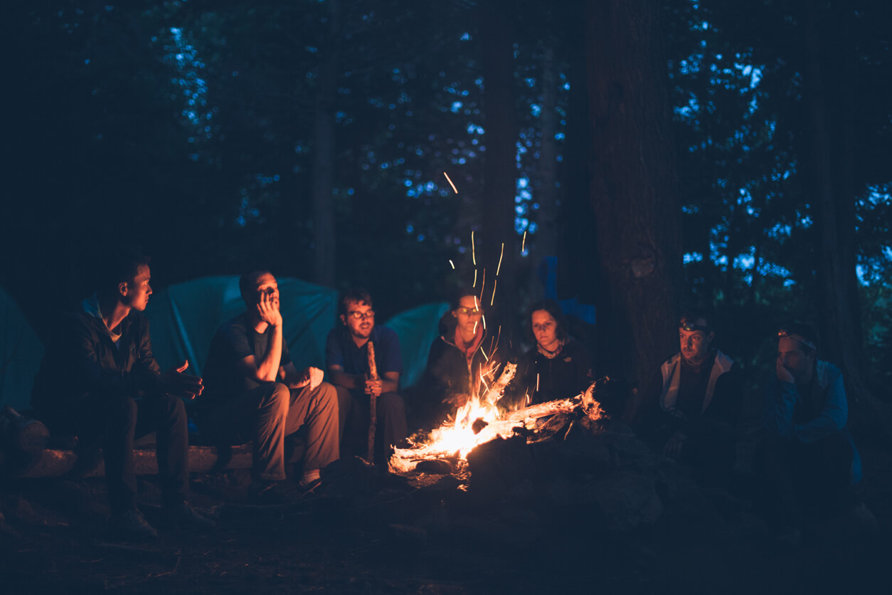 people gathered around a fire in a camping